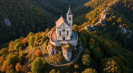 Historic church perched atop hilltop surrounded by lush autumnal forest