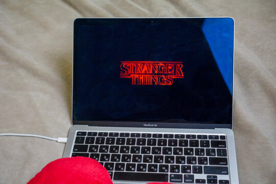 Bratislava, Slovakia, Europe - Dec 20, 2025: stranger things logo on laptop screen apple macbook air on bed indoor home setting netflix series title on display with copy space for banner design