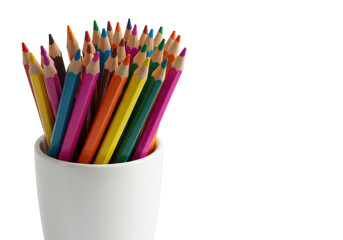 New rainbow colored pencils sharpened to a point in a white ceramic cup on a high-key studio background with copy space. Concept of creativity and inspiration.
