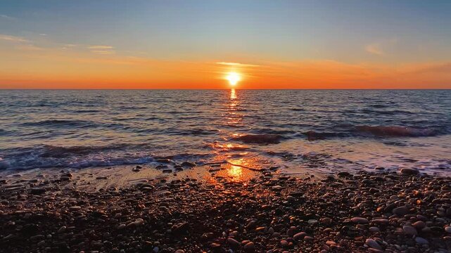 Orange sunset in Tuapse, sea waves with foam run to the shore. The Black Sea coast at sunset in the clouds. Pebble beach in the village of Agoy. The stormy sea in the evening. 4К