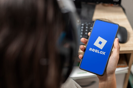 A teen holding a mobile with Roblox logo