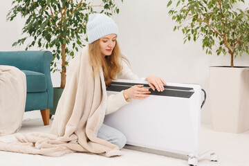 Woman adjusting portable heater settings at home in winter to save energy