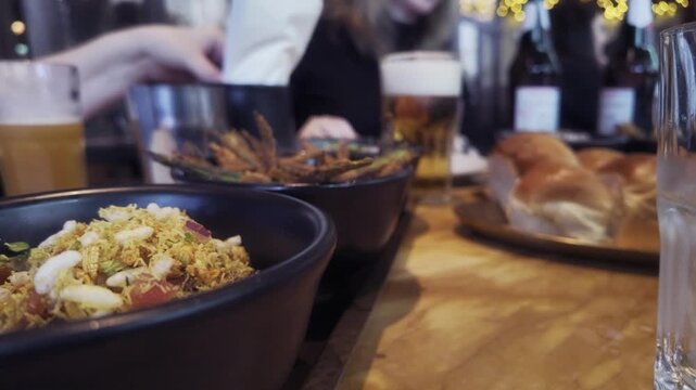 Indian Curry Dishes on Restaurant Table with Beer in Birmingham, England.
Close-up view of freshly served Indian curry dishes on a wooden table inside a modern Indian restaurant in Birmingham, England