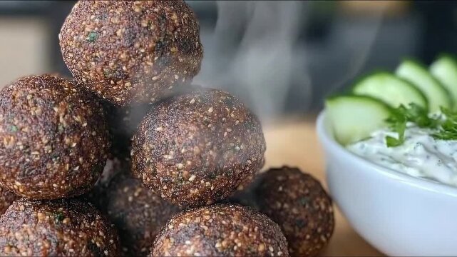 Delicious falafel balls with tzatziki sauce on wooden table