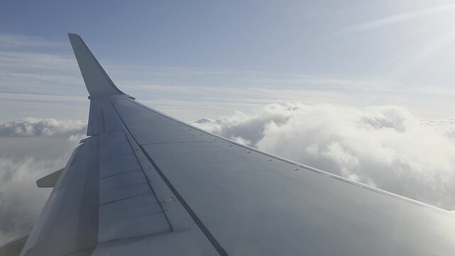 Plane wing over cloudscape view from airplane window during flight