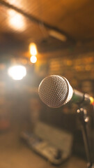 Obraz premium A close-up of a stage microphone, with an out-of-focus background of warm lights, creating a concert or event atmosphere.