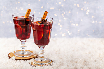 Mulled wine. Festive holiday drinks served in elegant glassware, garnished with cinnamon sticks and star anise, resting on soft artificial snow, creating warm and inviting atmosphere for celebrations