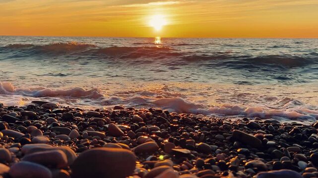 Orange sunset in Tuapse, sea waves with foam run to the shore. The Black Sea coast at sunset in the clouds. Pebble beach in the village of Agoy. The stormy sea in the evening. 4К