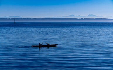 Father and son kayak on the calm seas at dawn in Port Townsend Washington