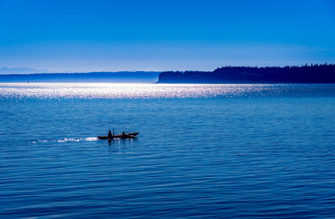 Father and son kayak on the calm seas at dawn in Port Townsend Washington