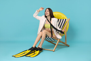 Businesswoman with flippers in deck chair on light blue background © New Africa