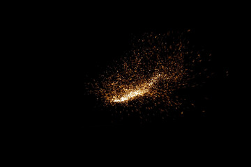 Concentrated burst of fiery golden particles igniting the darkness, a sweeping trail of sparks arcing through the black void like a comet made of glittering light and burning dust

