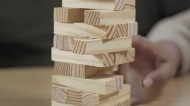 People enjoying a wooden block stacking game at home, focusing on precision, balance, and shared leisure time around a table.