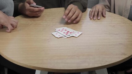 People enjoying a relaxed card game at a table at home, holding playing cards and focusing on strategy and social interaction in a casual indoor setting. - Powered by Adobe