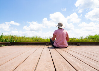 Senior Woman Sitting on the Dock at the Indiangrass Preserve of the Coastal Prairie Conservancy in Waller, Texas