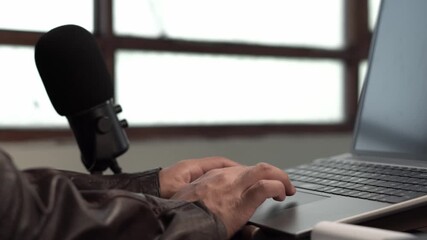 Businessman working on a laptop with a microphone on the desk, representing virtual meetings, content creation, and professional online activity. - Powered by Adobe