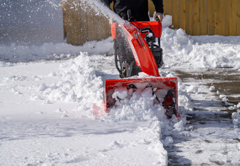 man removing snow on the driveway of the house by snow blower