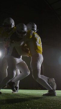 Full vertical shot of American football quarterback in blue jersey spurting downfield to advance ball to end zone, then getting tackled by rival team players in yellow uniforms