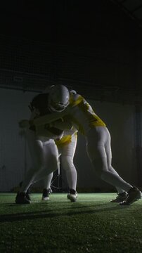 Full vertical shot of American football players intercepting and tacking rival fullback running downfield with ball, while practicing blocking technique at stadium
