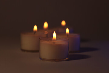 Soft focus. blur Burning candles in dark. Evening, night Light and shadow brown background. Minimalist still life.