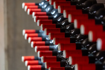 Fototapeta premium Wine bottles stacked horizontally on cellar racks, selective focus winery background