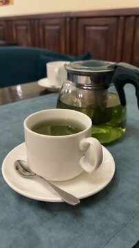 mint tea green tea Green tea with currant leaves and mint in glass teapot and cup on black background
