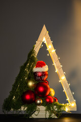 Modern DIY wooden Christmas tree with LED lights, moss, red balls and ornaments on a neutral background