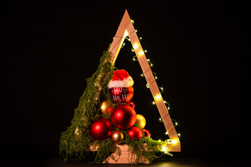 Modern DIY wooden Christmas tree with LED lights, moss, red balls and ornaments on a neutral background