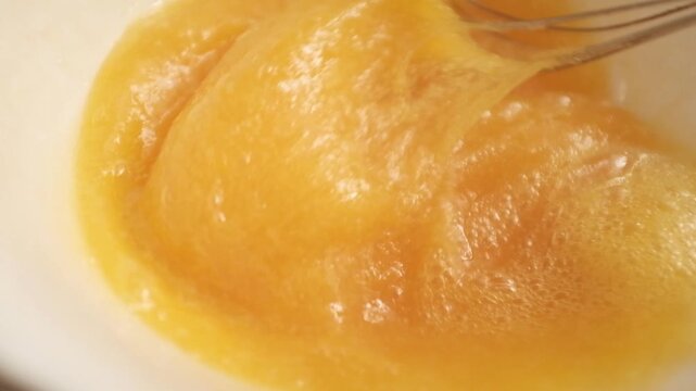 Closeup slow motion video of uncooked raw eggs. Whisking eggs for an omelette, scrambled eggs, baking, egg dishes. Preparing food, home cooking, cooking process.