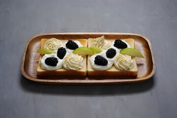 Two slices of toast with cream, blackberries, and pear on wooden tray