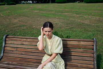 Woman on bench in park thoughtful and alone wearing light dress outdoors, portrait with authenticity inclusivity mood