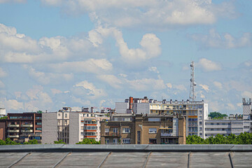 Obraz premium Bright clouds float over a modern urban skyline in Toulouse, showcasing a mix of low-rise and high-rise structures. The vibrant blue sky adds to the lively atmosphere of the city