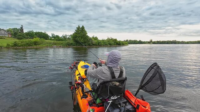 Kayak fishing game, angler at weedy lake pond, fishing pdl kayak during tournament. Sport and bass fishing activity in the morning on pedaling fishing kayak. Water hobby and active lifestyle.