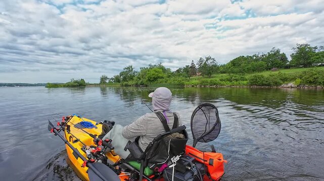 Kayak paddle at lake or pond during fishing game sport action. Fisherman with fishing gear on pedal kayak paddles and casting. Leisure active lifestyle recreation and sport activity.