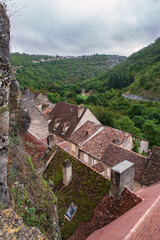 Houses in the town of Rocamadour seen from above, with their roofs, the valley and the forest