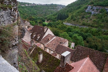 Houses in the town of Rocamadour seen from above, with their roofs, the valley and the forest