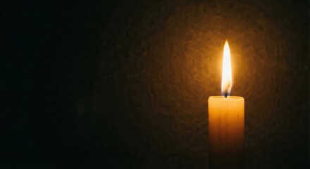 Candle flame glowing in darkness symbolizing hope and remembrance