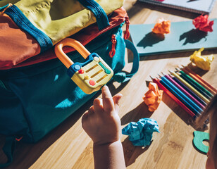 Vibrant closeup of a childs hand reaching for a toy padlock on a colorful school backpack. A metaphor for safety, curiosity, and learning, ideal for educational or parenting marketing.