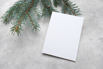 Blank Christmas greeting card mockup with evergreen branches on a textured gray surface, ideal for holiday designs and festive messages with copy space