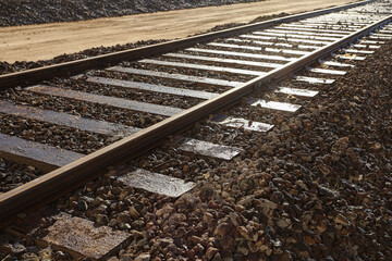 Naklejka premium Railway tracks perspective view. Steel rails on gravel ballast. Transportation infrastructure detail. Industrial travel route outdoors. Linear pattern and direction. Logistics transport concept.