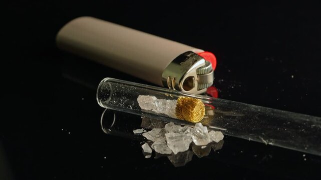 Crack cocaine drug in rocks or hard crystals with smoking crack pipe on the table. Illicit drugs very potent and addictive for sale in the streets and contribution to homelessness and addiction crises