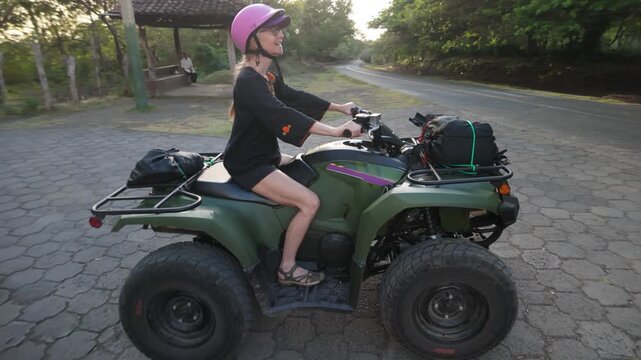 A mature woman enjoys riding a quad on Ometepe Island, exploring the scenery and the local paths during her adventure.