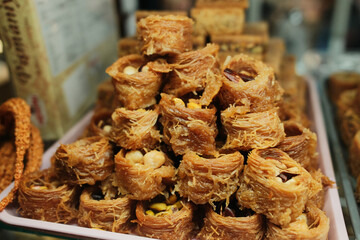 Close up view of spiral shaped kataifi pastries with nut filling, resembling cinnamon rolls, displayed in a traditional sweet shop in Bosnia and Herzegovina. Rich texture and handmade dessert concept.