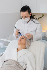 Injection-free mesotherapy or electroporation. Beautician doctor makes client middle-aged woman...