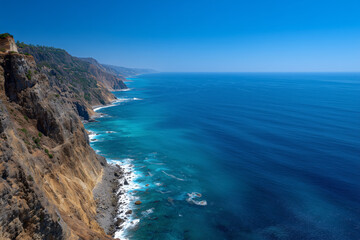 Breathtaking ocean waves crashing against rugged rocky coastline on a sunny day