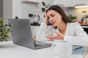 Young woman at home reads laptop result feels upset after lost game or rejected project clicks...