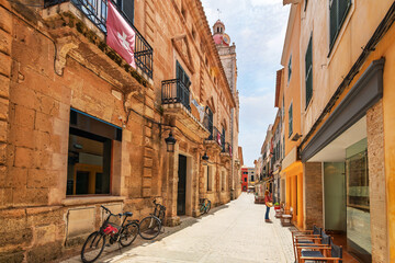 A narrow street of colorful shops and cafes in the historic old town of Ciutadella de Menorca, Spain, on the Mediterranean Balearic island of Menorca. © Kirk Fisher