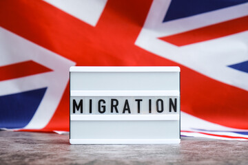 Lightbox with text MIGRATION flow. National symbol of Great Britain. British wave the UK silky flag background. Concept of human migration crisis and population refugee movement. Demographic change 