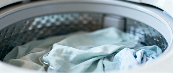 Top view of light-colored clothes soaked in water inside washing machine drum before wash cycle.