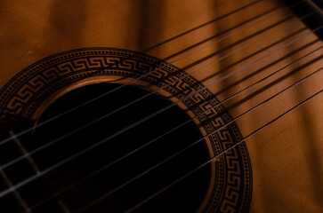 Obraz premium Close-up photo of an acoustic guitar with shadows. Guitar strings, neck, frets and body
